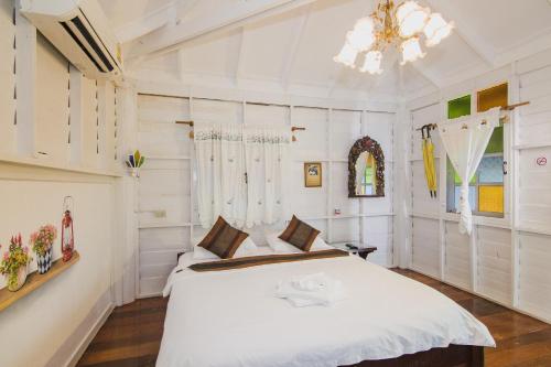 a bedroom with a white bed and a chandelier at Baan Imm Sook Resort in Chao Lao Beach