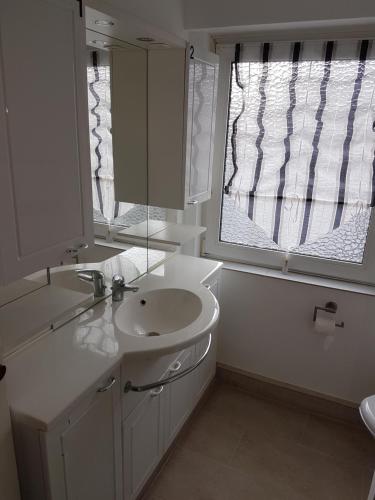 a white bathroom with a sink and a window at Zimmer Müller in Wesseling