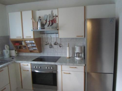a kitchen with white cabinets and a stainless steel refrigerator at Ferienwohnungen Fuchshuber in Neukirchen vorm Wald