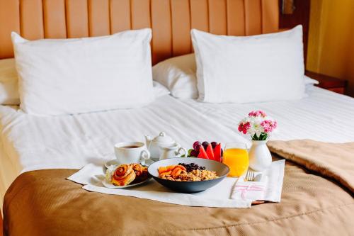 a breakfast tray with a bowl of food on a bed at GRAND HOTEL Kielce in Kielce