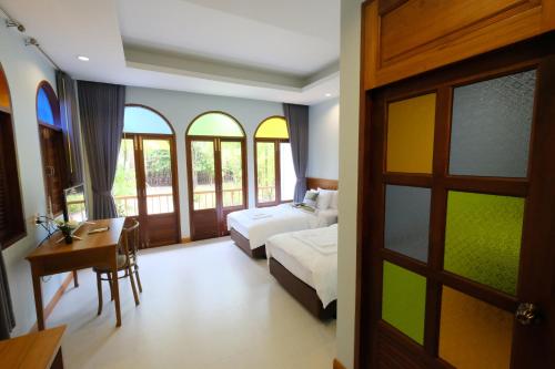 a bedroom with a bed and a desk and a bed and window at Baan Imm Sook Resort in Chao Lao Beach