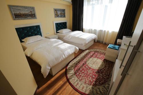 a hotel room with two beds and a rug at Altai Business Hotel in Almaty