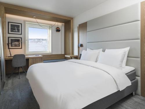 a bedroom with a large white bed and a desk at Radisson Blu Hotel Tromsø in Tromsø