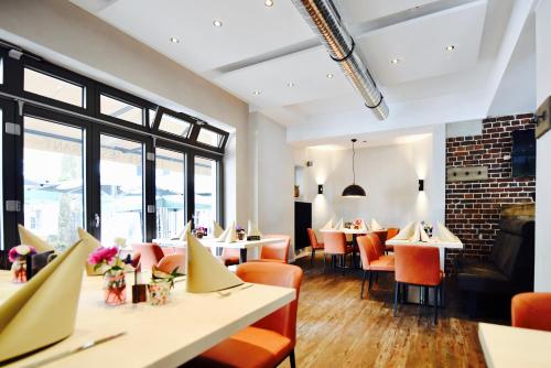 een eetkamer met tafels, stoelen en ramen bij cityhotel in Bocholt