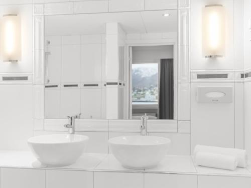 a white bathroom with two sinks and a mirror at Radisson Blu Hotel Tromsø in Tromsø