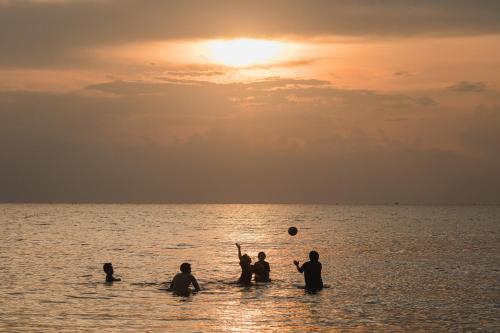 a group of people playing in the water at the beach at Baan Imm Sook Resort in Chao Lao Beach