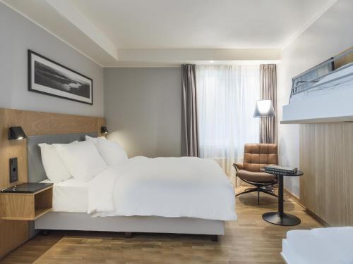a hotel room with a white bed and a chair at Radisson Blu Hotel Tromsø in Tromsø
