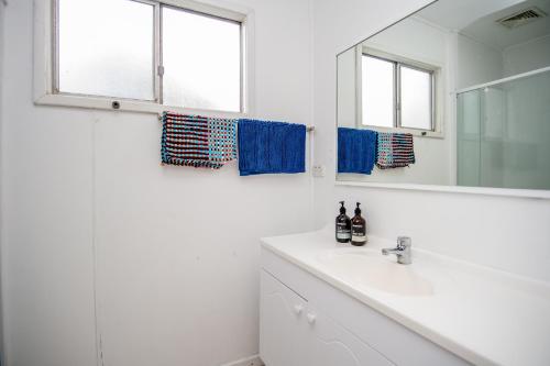 a white bathroom with a sink and a mirror at The Gee Beach House in Guilderton