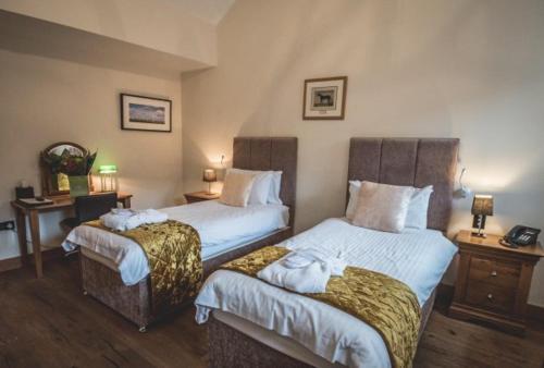 a hotel room with two beds and a desk at The Saddle Room in Middleham