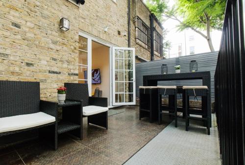 um pátio com cadeiras e mesas e uma parede de tijolos em The Mornington Camden Female only Hostel em Londres