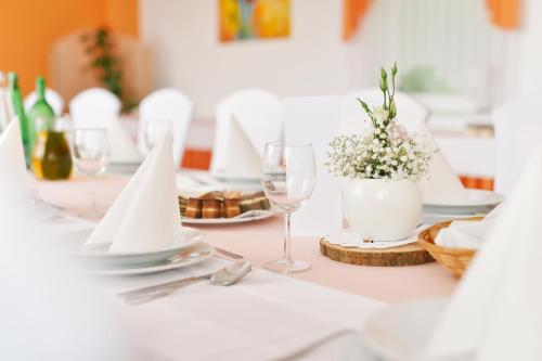 una mesa blanca con copas de vino y flores. en Penzion Letališče en Murska Sobota