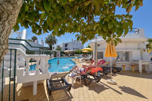 a pool at a resort with a woman sitting in a chair at Verde Pino in Vilamoura