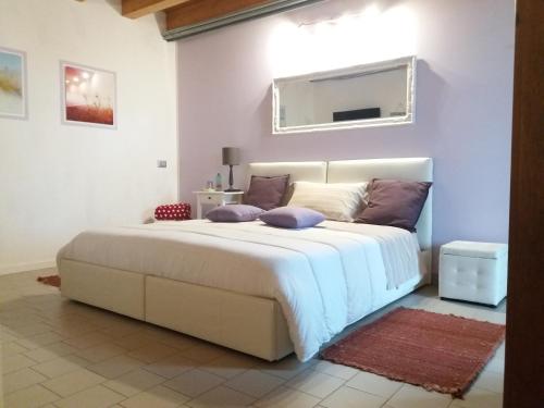 a bedroom with a large white bed with purple pillows at Villa Posta Vecchia in Loreo