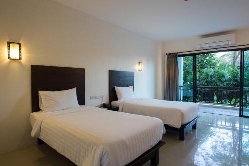 a hotel room with two beds and a balcony at Wilacha Chiang Rai in Chiang Rai