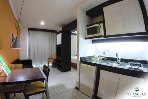 a kitchen and dining room with a table and a microwave at Triângulo Apart Hotel in Vitória