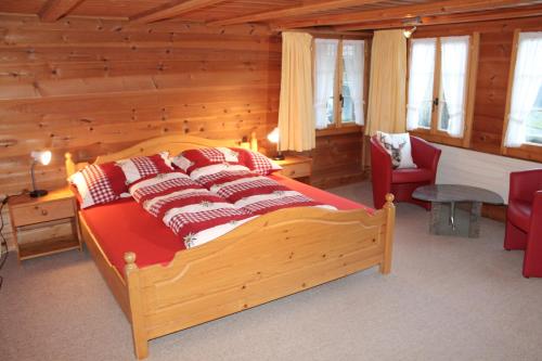 レンクにあるChalet Weissenbergのベッドルーム1室(大型木製ベッド1台、赤い枕付)