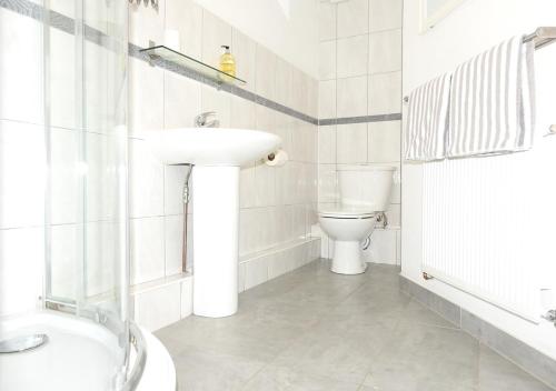 La salle de bains blanche est pourvue d'un lavabo et de toilettes. dans l'établissement Harbour View 4, à Gosport