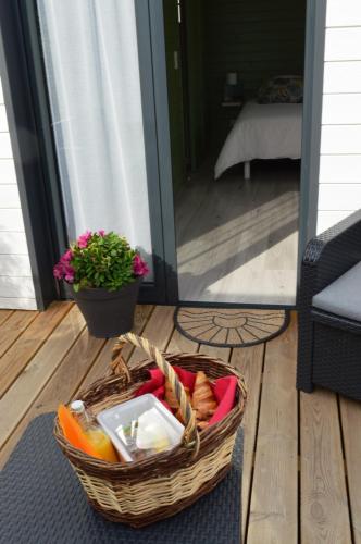 un panier de nourriture sur une terrasse couverte avec une plante dans l'établissement Au Cap Norwoe, à Saint-Quentin-en-Tourmont
