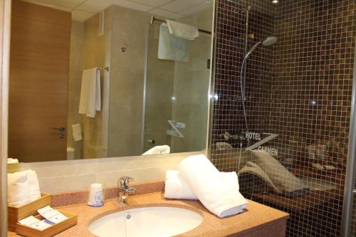 ein Bad mit einem Waschbecken und einer Dusche mit einem Spiegel in der Unterkunft Hotel Carmen in La Cala de Mijas