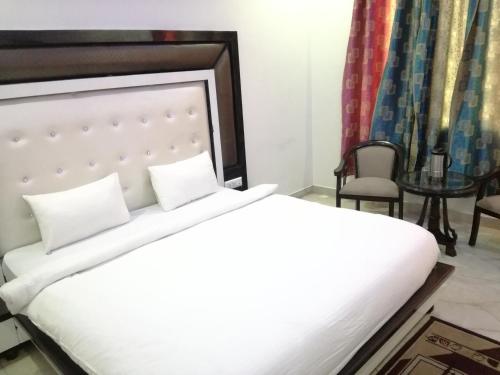 a bedroom with a bed and a chair and a table at Hotel Dhanraj Palace in Bharatpur