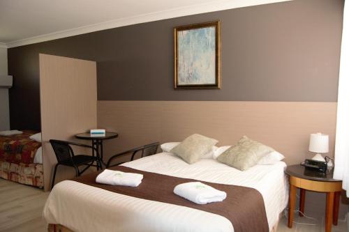 a hotel room with a bed with two towels on it at Civic Motor Inn in Cowra