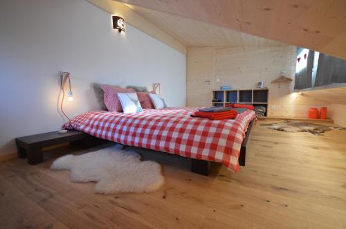 a bedroom with a bed with a red and white checkered blanket at Chalet Rouge Coeur in Fenalet Sur Bex