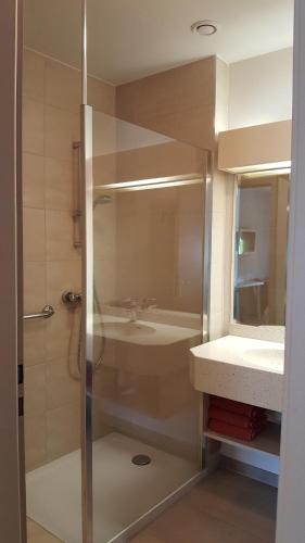 a bathroom with a shower and a sink at Hotel Les Remparts in Kaysersberg