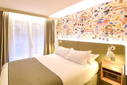 a bedroom with a bed and a painting on the wall at Hôtel Des Artistes in Lyon
