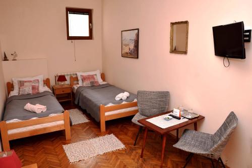 a room with two beds and a table and chairs at Sobe Gajić Sremski Karlovci in Sremski Karlovci