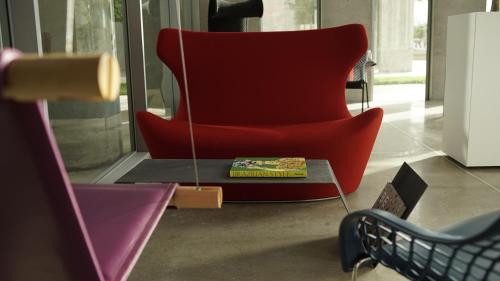 a red chair with a book on a table in a room at Bossa Nova Beirut Hotel in Beirut