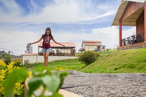 a woman walking down a gravel road in front of a house at The Realm in Coonoor