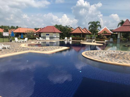 a pool at a resort with blue water and chairs at Mae Phim, Rayong, Bali Residence Villa in Mae Pim