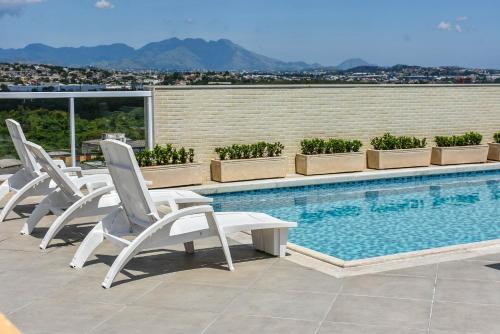 uma fila de cadeiras sentadas ao lado de uma piscina em Mont Blanc Suites Duque de Caxias em Duque de Caxias