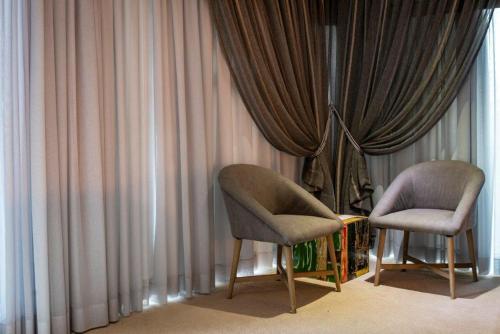 two chairs sitting in front of a window with curtains at Middelwater Farm Hotel in Bloemfontein