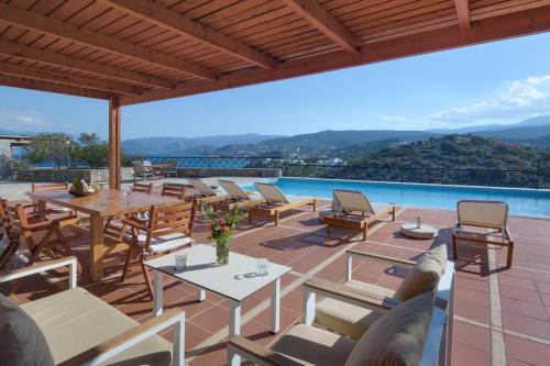 
a patio area with chairs, tables, and tables with umbrellas at Miramare Resort & Spa in Agios Nikolaos

