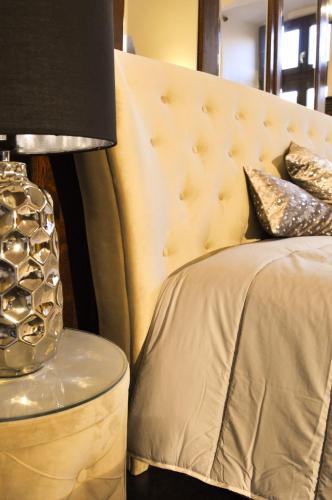 a bed with a headboard and a table with a lamp at Belga Boutique Panzió in Debrecen