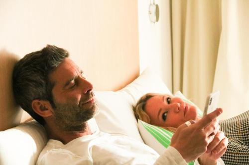 a man and a child laying in a bed looking at a remote control at SmartRoom Barcelona in Barcelona
