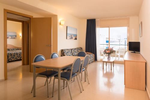 a living room with a table and chairs in a room at htop Royal Sun Suites 4Sup - Fun in Santa Susanna