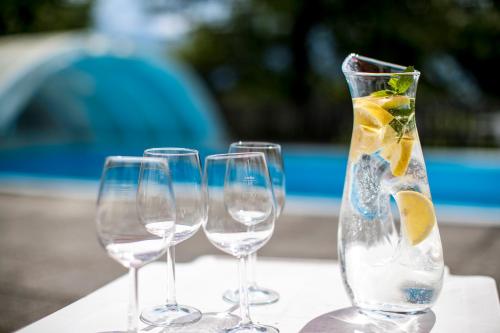 four wine glasses and a vase with lemons in it at Hotel Gasthof zur Linde in Mariahof
