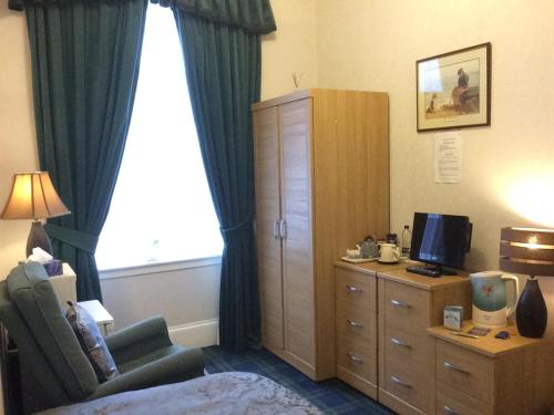 
a room with a bed, chair, desk and a lamp at Crawfords Guest house in Peterhead
