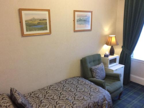 
a hotel room with a bed, chair and a lamp at Crawfords Guest house in Peterhead
