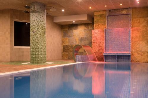 a large swimming pool in a room with a tv at htop Palm Beach SPA - Fun in Lloret de Mar