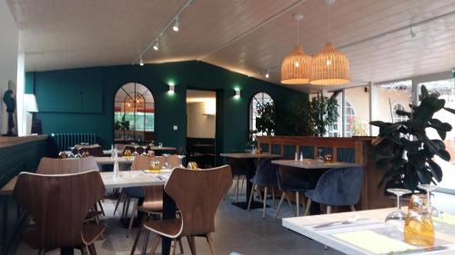 a restaurant with tables and chairs and a green wall at Logis Hotel Le Chêne Vert in Bollène
