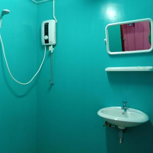a blue bathroom with a sink and a mirror at Rub Lom Chom Klong Homestay in Chumphon
