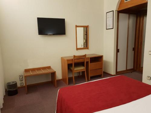 a bedroom with a desk and a television on the wall at Luso Brasileiro in Póvoa de Varzim
