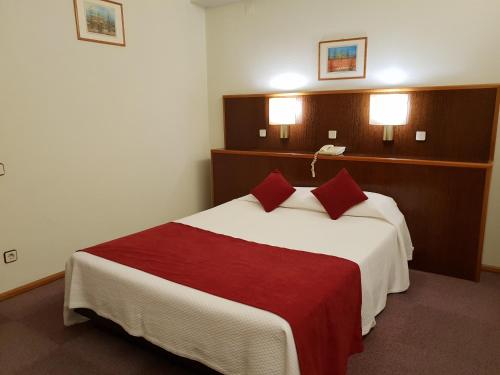 a hotel room with a bed with a red blanket at Luso Brasileiro in Póvoa de Varzim