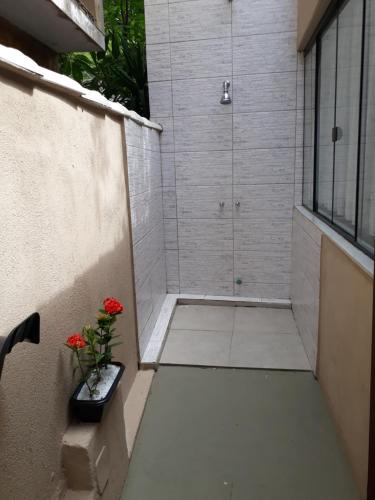 a bathroom with a shower with a vase of red flowers at Suítes Praias de Búzios in Búzios