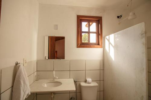 ein Bad mit einem Waschbecken, einem WC und einem Fenster in der Unterkunft Pousada Casa de Jorge in Lençóis