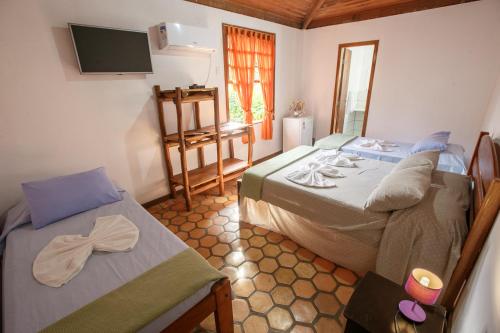 a bedroom with two beds and a tv on the wall at Pousada Casa de Jorge in Lençóis