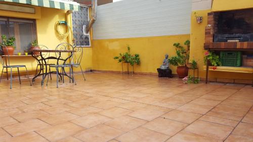 a patio with chairs and a table and a yellow wall at Atic Casa Llebra in Roquetas